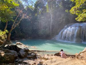 a woman sitting in front of a waterfall at Jim Guesthouse in Kanchanaburi