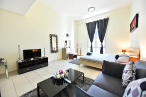 a living room with a couch and a tv at Spacious Fully Furnished Studio Apt - Next to Metro, 5 Mins from Mall - TNY in Dubai