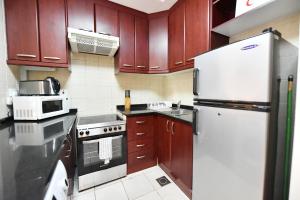 a kitchen with wooden cabinets and a white refrigerator at Spacious Fully Furnished Studio Apt - Next to Metro, 5 Mins from Mall - TNY in Dubai