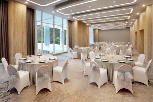 um salão de banquetes com mesas brancas e cadeiras brancas em ibis Styles Bogor Pajajaran em Bogor