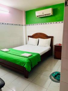 a bedroom with a bed with a green wall at Hoang Anh Hotel in Ho Chi Minh City