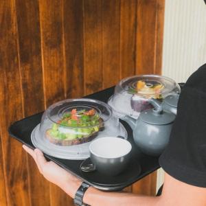 a person holding a tray with food on it at ARTOTEL Haniman Ubud in Ubud