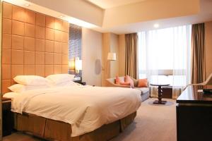 um quarto de hotel com uma cama grande e um sofá em Crowne Plaza Yantai Sea View, an IHG Hotel em Yantai