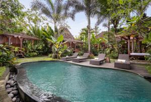 a swimming pool in a villa with lounge chairs at Madani Antique Villas in Ubud