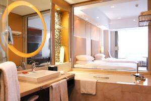 uma casa de banho com um lavatório e uma cama num espelho em Crowne Plaza Yantai Sea View, an IHG Hotel em Yantai