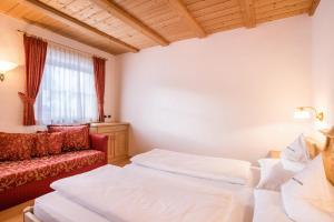 una habitación de hotel con dos camas y un sofá en App Lisüra Boè, en Corvara in Badia
