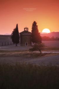 an old barn with the sunset in the background at Agriturismo Poggio Tobruk in Pienza