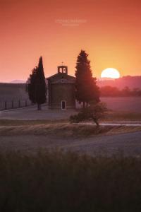 un antiguo granero con la puesta de sol en el fondo en Agriturismo Poggio Tobruk, en Pienza