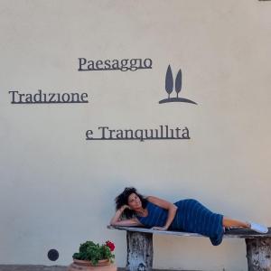 a woman laying on a bench under two signs at Agriturismo Poggio Tobruk in Pienza