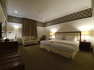 a hotel room with a large bed and a chair at The Plaza Hotel Balanga City in Balanga