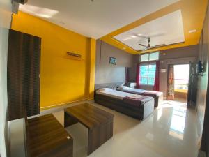 een slaapkamer met een bed en een gele muur bij APURBA GUEST HOUSE in Jorhat