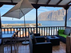 einen Balkon mit Stühlen, einem Sonnenschirm und dem Meer in der Unterkunft Penthouse de Roca in Poblado Marinero in Santiago del Teide