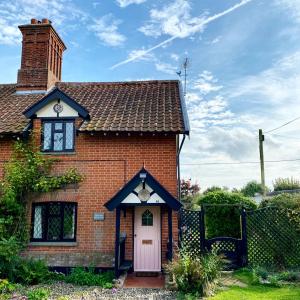 a red brick house with a white door at Piglet Cottage. A well equipped home from home. in Uggeshall