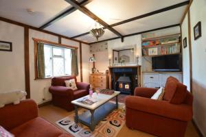 a living room with couches and a table and a fireplace at Piglet Cottage. A well equipped home from home. in Uggeshall