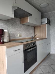 uma cozinha com armários brancos e um forno com placa de fogão em Ferienwohnung Reiter em Ummanz