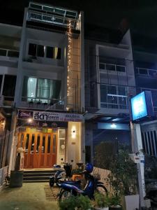 Una motocicleta estacionada frente a un edificio por la noche en สีดา​ โฮสเทล en Phetchaburi