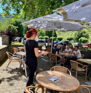 a woman standing in front of a table with an umbrella at Pension Dören in Bruttig-Fankel