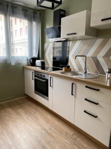 a kitchen with white cabinets and a sink at les Hallettes du havre hyper centre 300 de la mer in Le Havre +8 photos