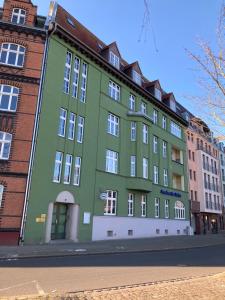 un edificio verde al lado de una calle en Apartments am Hafen, en Stralsund