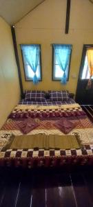een groot bed in een kamer met ramen bij Eco Bungalow in Ko Phayam