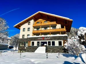 un gran edificio con nieve delante en SCHÖNIS-Landhotel, en Bad Mitterndorf