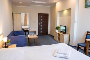 a hotel room with a bed and a couch and a tv at Hotel Kardamon in Tarnów