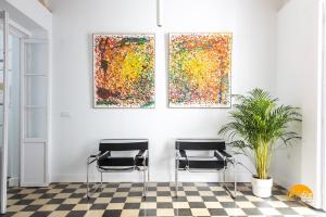 zwei Stühle in einem Zimmer mit drei Gemälden an der Wand in der Unterkunft La Casa del Alfarero by Cadiz Time in Cádiz