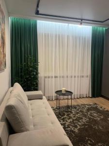 sala de estar con sofá blanco y cortinas verdes en Апартаменти в центрі Тернополя en Ternopilʼ