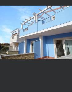 ein blau-weißes Haus mit einem Balkon in der Unterkunft Casa Silvia Climatizzata, giardino privato e posto auto privato in Viddalba