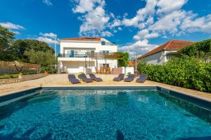 a swimming pool in front of a house at Apartments Luka & Lorena in Galovac