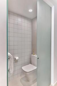 a bathroom with a toilet and a white tiled wall at lyf Farrer Park Singapore in Singapore