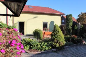 una casa amarilla con un banco en el jardín en Zaļais Stūrītis - holiday house with a sauna, en Liepāja
