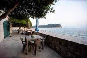 a table and chairs with an umbrella and the ocean at Vila Il Pescatore in Petrovac na Moru