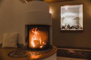 a fireplace in a living room with a fire in it at Hotel Villa Waldheim in San Candido