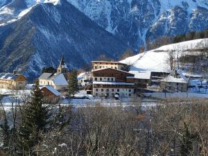 een dorp in de sneeuw met bergen op de achtergrond bij Appartement rez de jardin montée de l'alpe d'Huez in La Garde