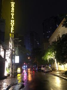 una calle de la ciudad por la noche con un cartel de neón en Hoàng Gia Hotel Nhân Hòa, en Hanói