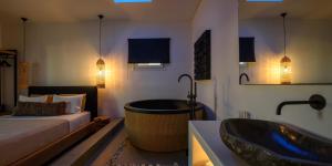 a bedroom with a tub and a bed and a sink at Olive Mykonos Villas in Ano Mera