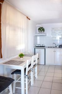 a white kitchen with a white table and chairs at SK studios & apartments in Neo Klima