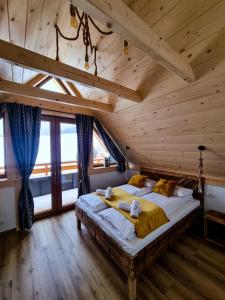 a bedroom with a large bed in a wooden ceiling at EM Gorce Resort komfortowe domki z sauną i jacuzzi in Waksmund