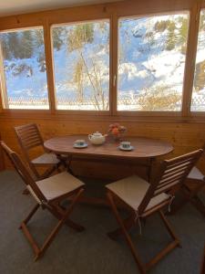 uma mesa de madeira e cadeiras num quarto com neve em Alpine apartment in Swiss village of Torgon em Torgon