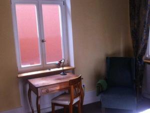 um quarto com uma secretária, uma cadeira e uma janela em Das Gaestehaus em Ofemburgo