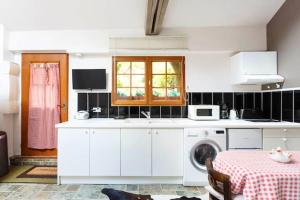 cocina blanca con lavadora y mesa en Studio avec jardin clos et wifi a Ville d'Avray a 1 km des pistes, en Champs-Sur-Marne