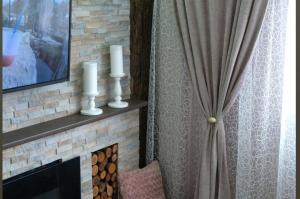 a fireplace with two candles and a curtain at Spa Apartman URBAN Life ZAJEČAR in Zaječar