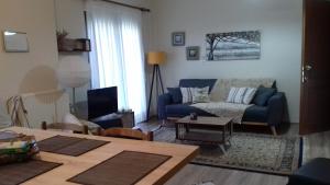 a living room with a blue couch and a table at Διαμέρισμα με κήπο in Orestiada