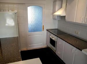 a small kitchen with a white door and a stove at Moderne Ferienwohnung Primavera in Colonia Sant Jordi