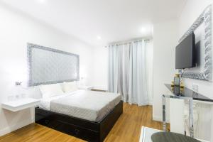 a white bedroom with a bed and a tv at Le Vingale in Funchal