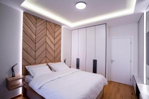 a bedroom with a white bed and a wooden headboard at Apartman G8 Deluxe in Pale