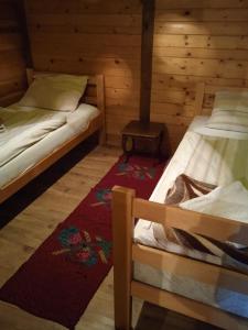 a room with two beds and a rug in a cabin at Holiday Home Vila Milka in Kremna