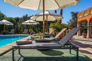 - une piscine avec 2 chaises longues et des parasols dans l'établissement Villa Ses Porrasses, à Selva