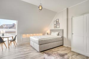 a white bedroom with a bed and a table at One Moment Boardinghouse - Porta Westfalica in Porta Westfalica
